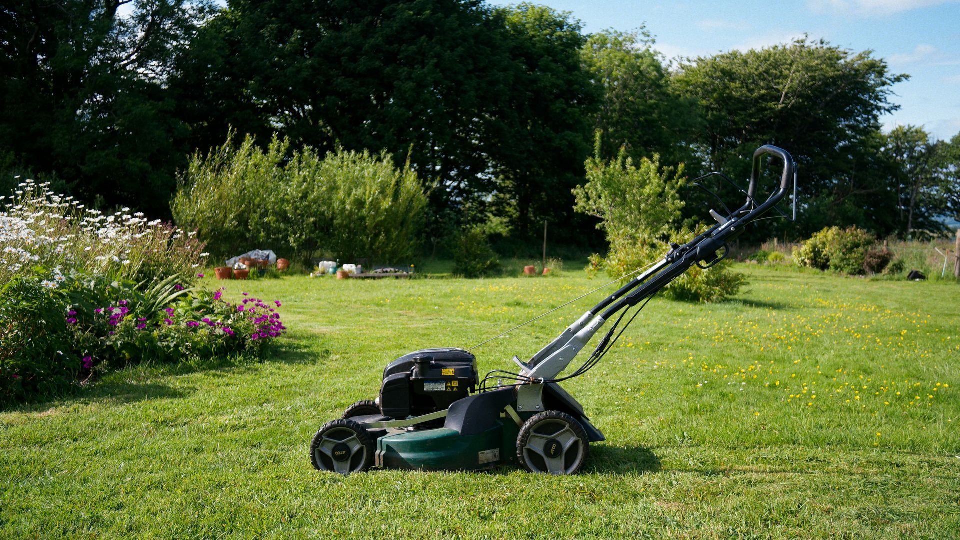A lawnmower sits on a grassy lawn
